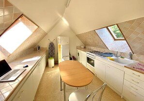 A kitchen with a dining table, a laptop, and a stove.