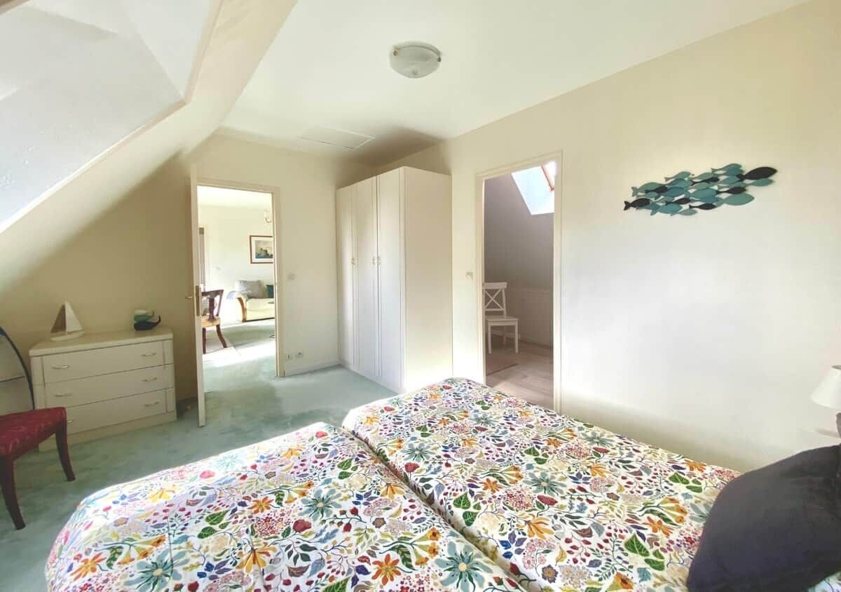 Een slaapkamer met een bed, een kaptafel, een stoel en een plafondventilator.