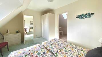 Een slaapkamer met een bed, een kaptafel, een stoel en een plafondventilator.