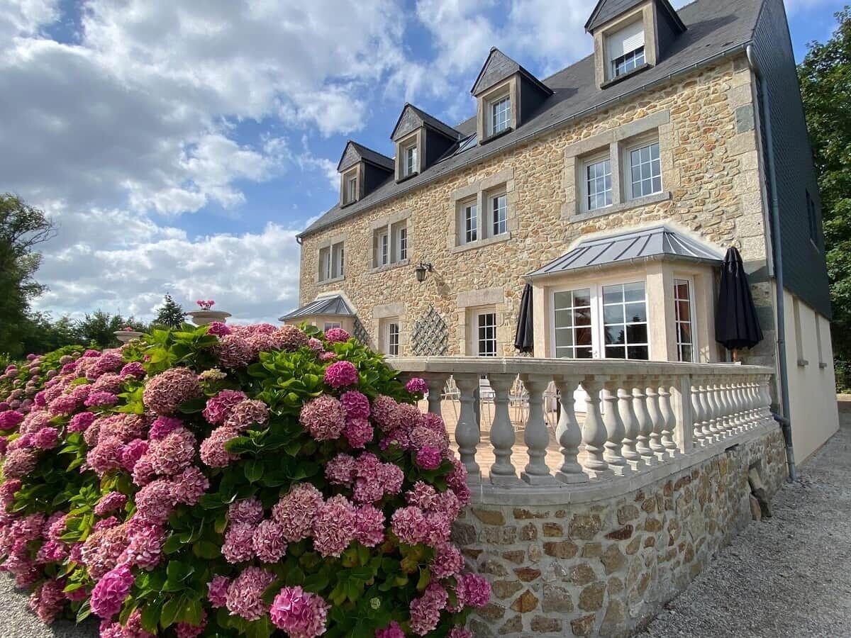 Un bâtiment en pierre doté de nombreuses fenêtres et d’un balcon.
