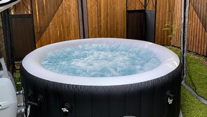 Un jacuzzi en un patio trasero con un cerco de madera y una planta pequeña.