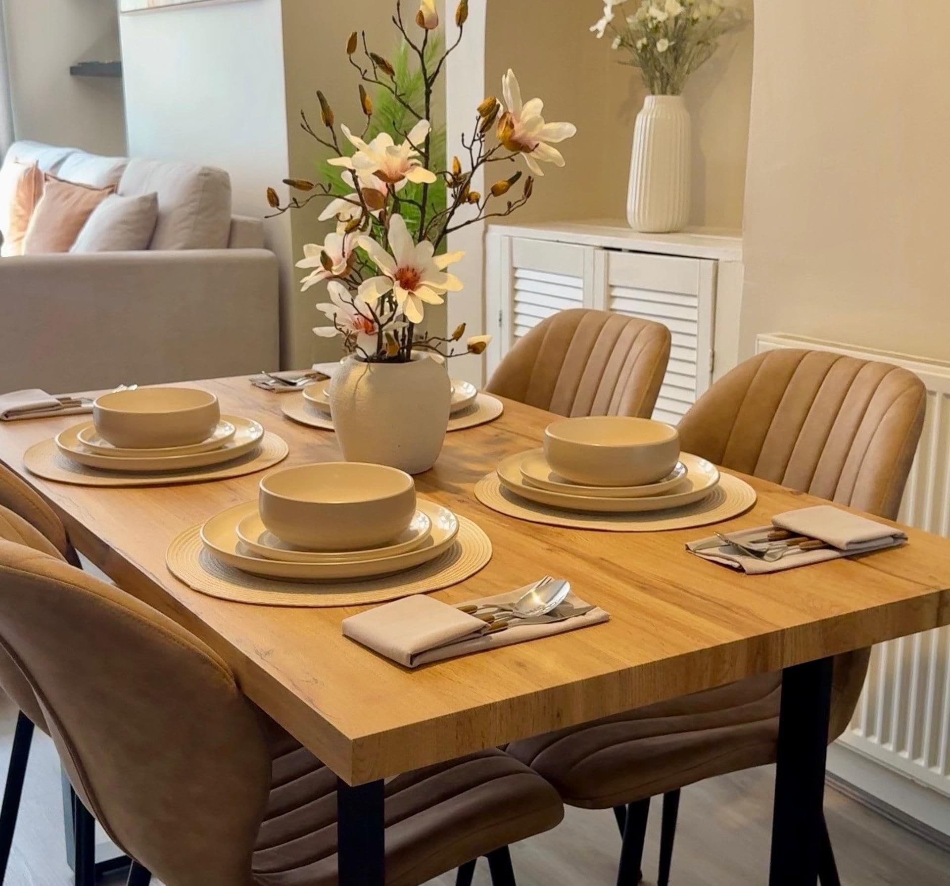 A dining table set with plates, bowls, and a vase with flowers.