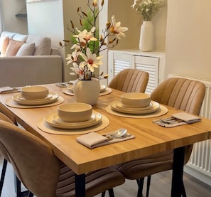 A dining table set with plates, bowls, and a vase with flowers. - St Julian House- Town Centre- Castle Park- Hot Tub (Colchester)