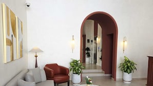 Una sala de estar moderna con un sofá, sillones, una mesa de centro y plantas en macetas.