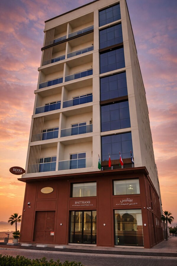 A multi-story hotel with balconies, a ground-level restaurant, and flags on the roof.