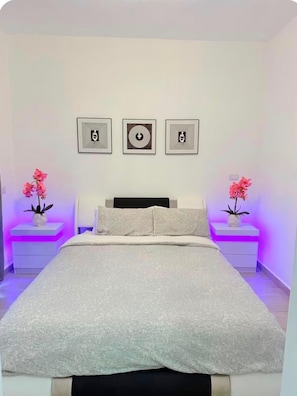 A bedroom with a bed, two bedside tables, and three framed artworks on the wall. - Bayahibe Stay (Bayahíbe)