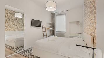 Une chambre moderne avec un lit, une télévision, une échelle et une fenêtre.
