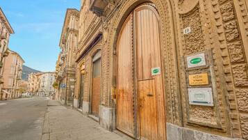 Un bâtiment doté de grandes portes en bois et d’une enseigne indiquant « L’Opéra » et « Chambres ».