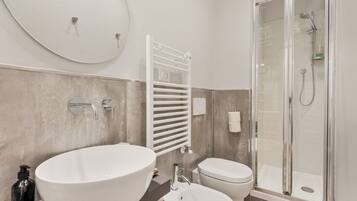 Une salle de bain moderne avec un grand lavabo ovale, des toilettes et une douche à parois de verre.