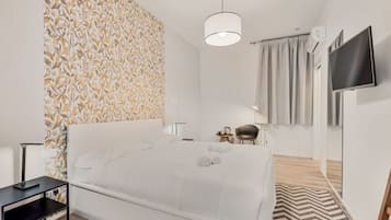 Une chambre d’hôtel avec un lit, un bureau, une chaise, une télévision et un mur décoré d’un motif.