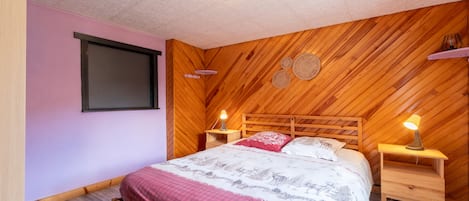 Un dormitorio con cabecera de madera, cama con ropa de cama estampada, lámparas de noche y estante montado en la pared.