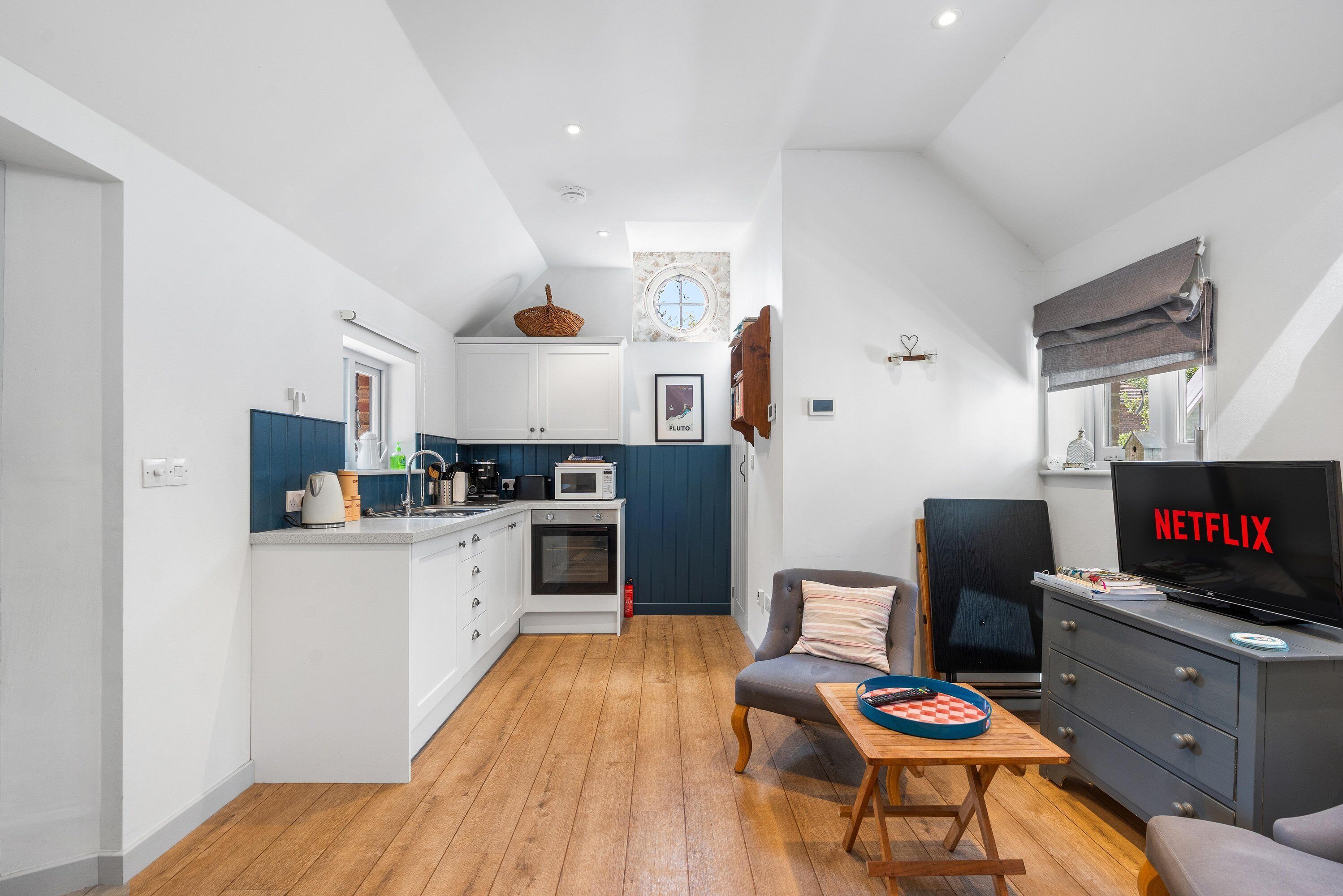 A compact living space with a kitchenette, a dining area, and a seating area with a television.