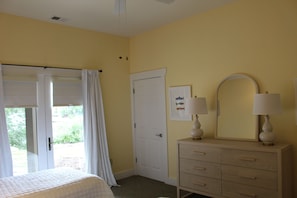 A room with a bed, a door, a dresser with two lamps, and a window with curtains. - Vista Cove Lake Lure- Private Cove & Game Room (Lake Lure)
