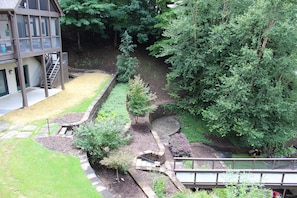 A landscaped garden with a brick pathway, a small tree, and a building with a balcony. - Vista Cove Lake Lure- Private Cove & Game Room (Lake Lure)