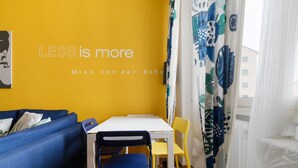 A room with a yellow wall, a white table, blue and yellow chairs, and a blue sofa. - Cozy 45 sqm flat, perfect for 3 people, located on the 5th floor of a building with elevator.The property is situated in the Calvairate district, a residential area characterized by the green spaces of Piazza Insubria & Viale Molise.The Porta Romana dist (Milan)
