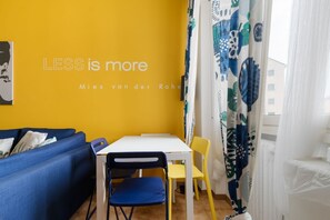 A room with a yellow wall, a white table, blue and yellow chairs, and a blue sofa. - Cozy 45 sqm flat, perfect for 3 people, located on the 5th floor of a building with elevator.The property is situated in the Calvairate district, a residential area characterized by the green spaces of Piazza Insubria & Viale Molise.The Porta Romana dist (Milan)