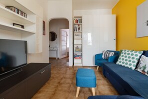 A living room with a television, a blue sofa, and a bookshelf. - Cozy 45 sqm flat, perfect for 3 people, located on the 5th floor of a building with elevator.The property is situated in the Calvairate district, a residential area characterized by the green spaces of Piazza Insubria & Viale Molise.The Porta Romana dist (Milan)