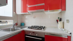 A kitchen with red cabinets, a stainless steel sink, and a gas stove. - Cozy 45 sqm flat, perfect for 3 people, located on the 5th floor of a building with elevator.The property is situated in the Calvairate district, a residential area characterized by the green spaces of Piazza Insubria & Viale Molise.The Porta Romana dist (Milan)