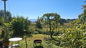 An outdoor patio with a table and chairs, surrounded by greenery and a view of distant mountains. - Apartment 'Fewo 3-Länder-Panorama' with Mountain View, Shared Terrace and Wi-Fi (Lindau)