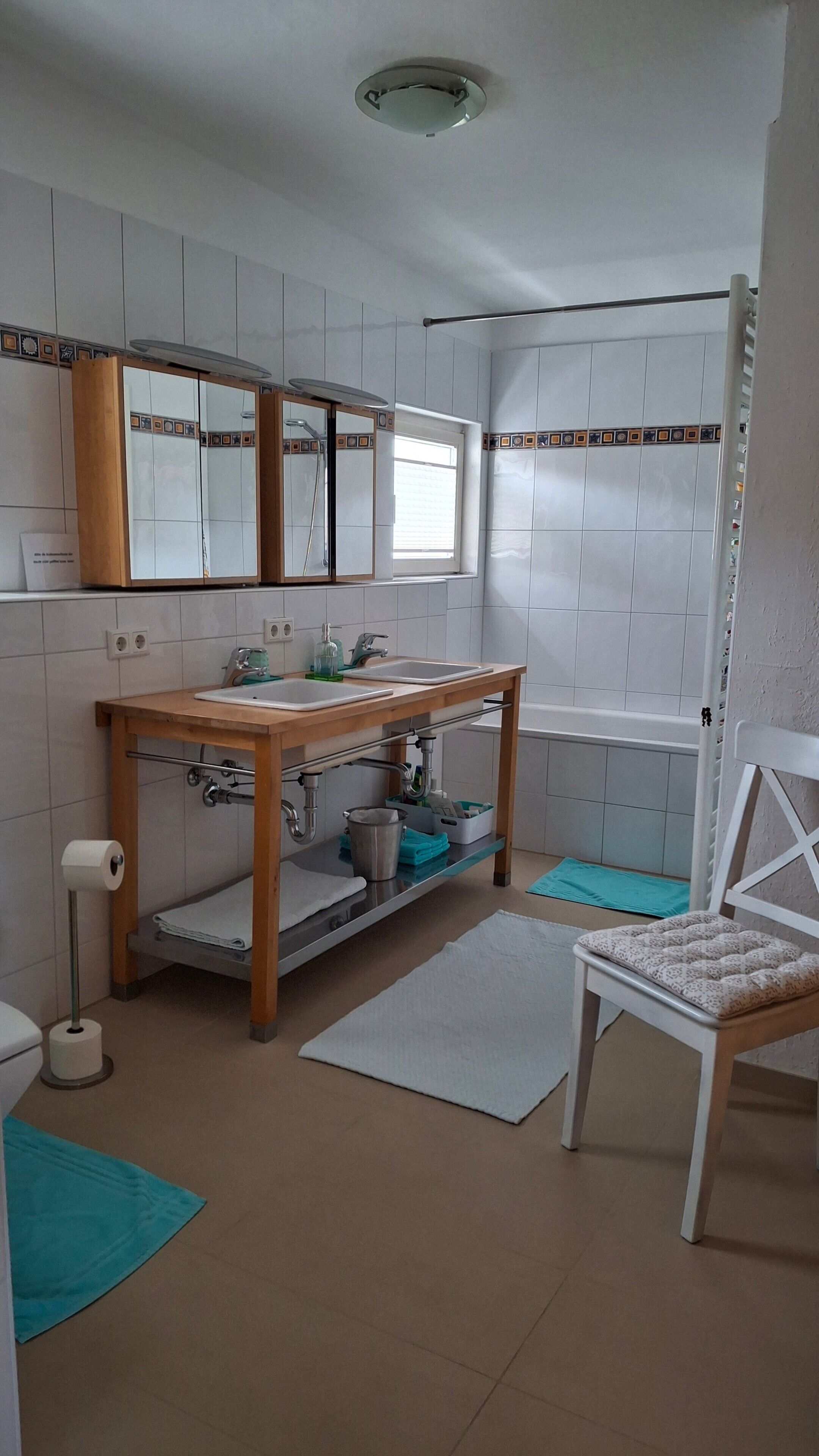 Ein Badezimmer mit einem Holzwaschtisch, einem Waschbecken, einem Spiegel, einer Toilette und einer Duschkabine.