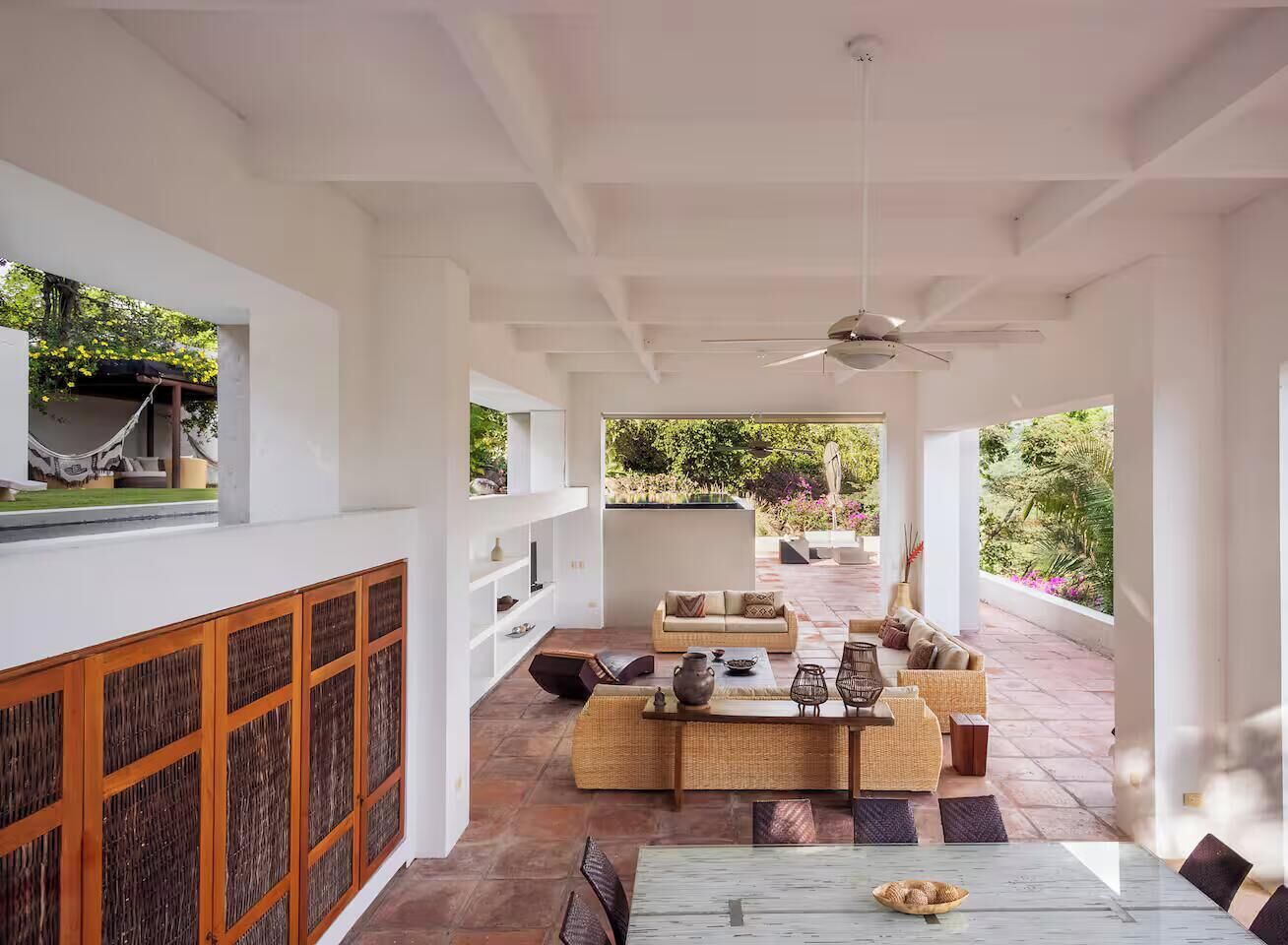 A spacious indoor area with a dining table, sofas, and a ceiling fan.