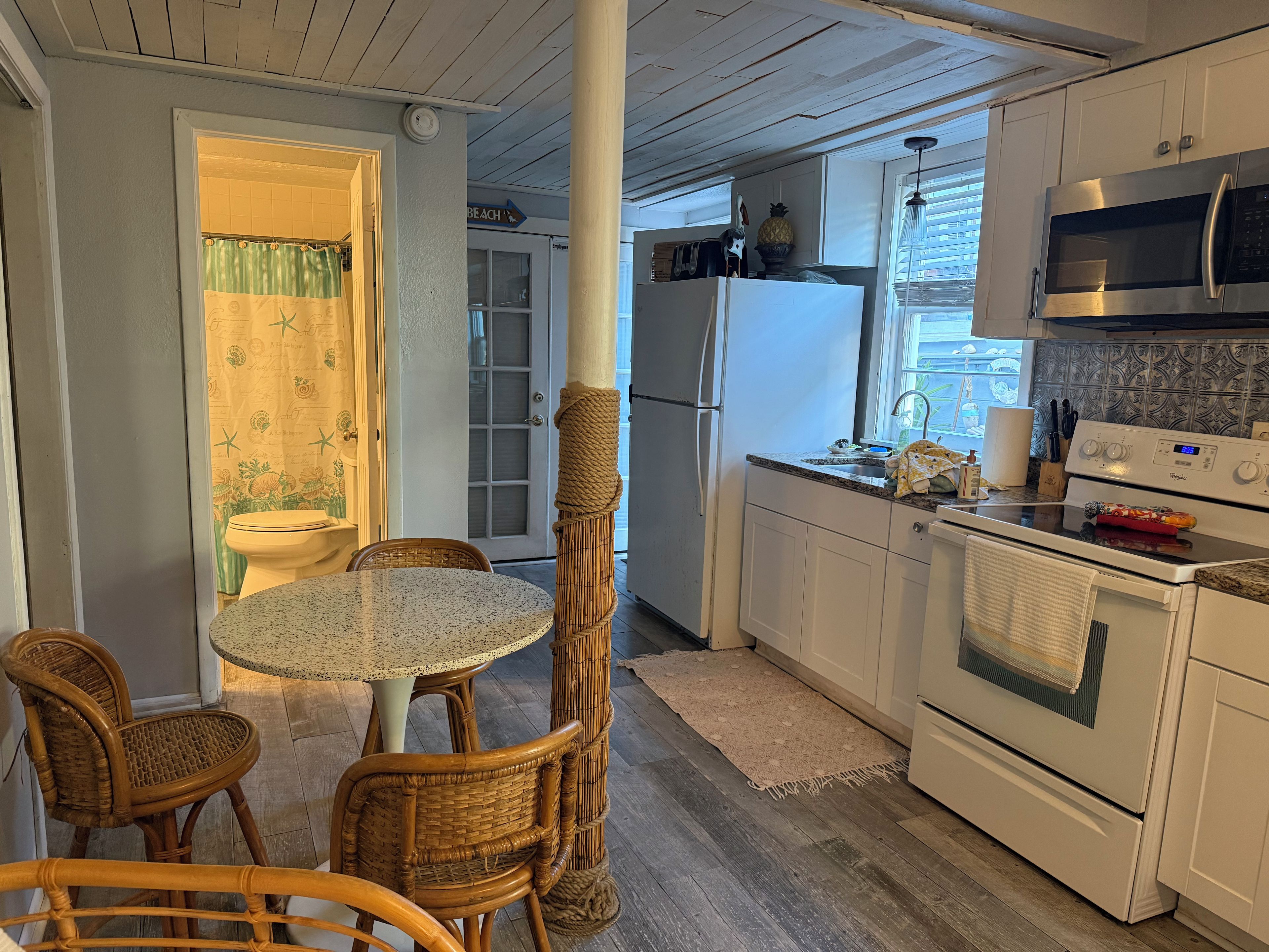 A kitchen with a dining area, featuring a refrigerator, microwave, stove, and a dining table with chairs.