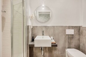 A bathroom with a glass shower enclosure, a white sink with a round mirror above it, and a toilet. - [RoomsCamera1] 5Terre-Near the station+A/C (La Spezia)
