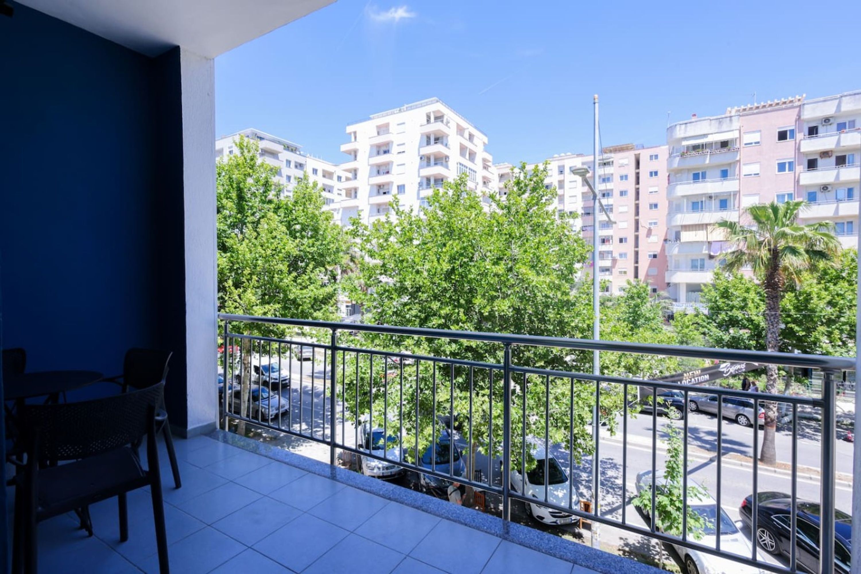 Un balcone con vista su una zona residenziale, comprensiva di auto parcheggiate e palazzi.