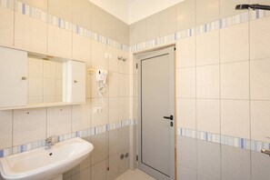 Een badkamer met een wastafel, een spiegel, een handdoekhouder en een deur.