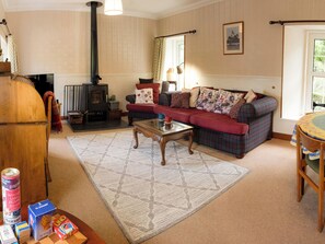 A cozy living room with a fireplace, a sofa set, a coffee table, and a television. - Curlew Cottage (Crianlarich)
