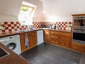 Eine Küche mit Holzausstattung, einer Waschmaschine, einer Kaffeemaschine und einem großen Backofen.