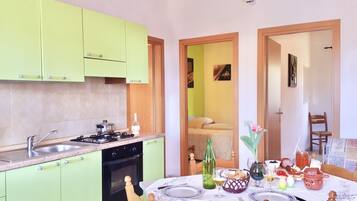 A compact kitchen with a gas stove, sink, and a dining area with a table set for two.