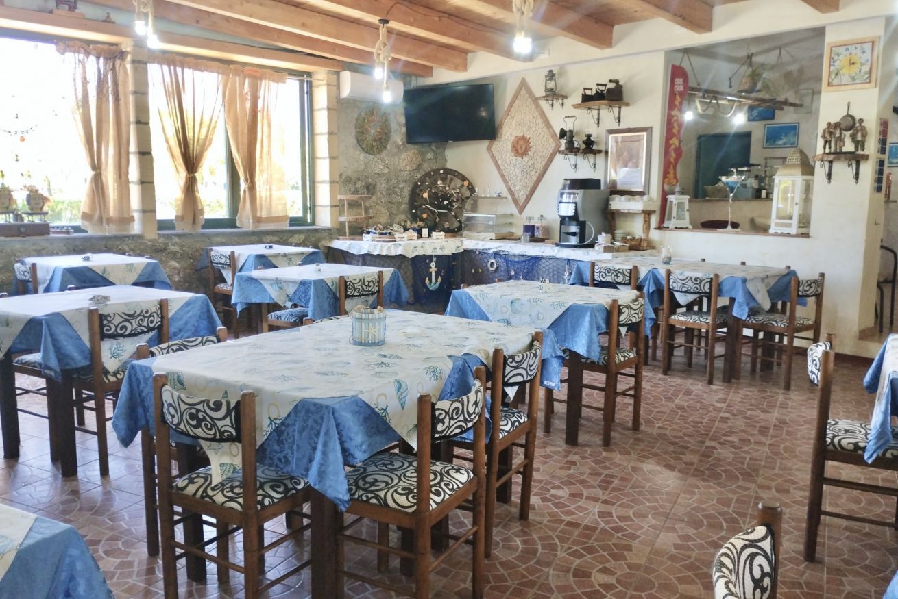 A dining area with multiple tables and chairs, a television mounted on the wall, and various decorative items.