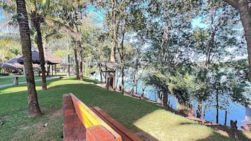 A park with a wooden bench, trees, and a body of water.