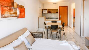 A hotel room with a bed, a dining table, chairs, a kitchen area, and a bathroom.