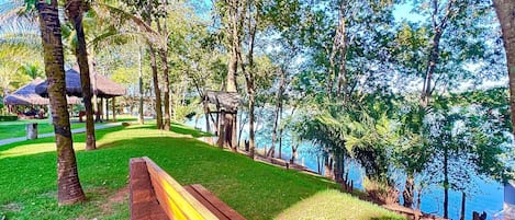 A park with a wooden bench, trees, and a body of water.