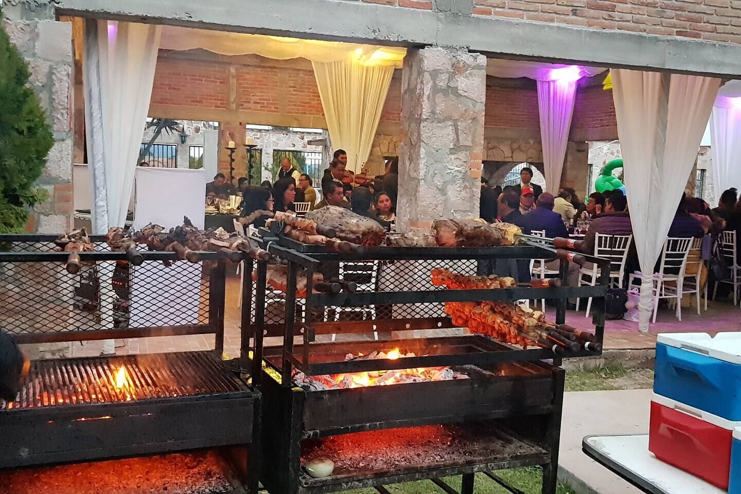 An outdoor dining area with multiple barbecue grills and tables.