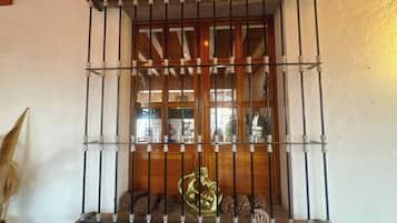 A window with metal bars and a decorative brass statue.