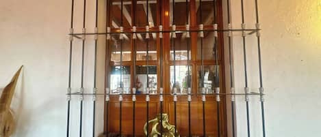 A window with metal bars and a decorative brass statue.