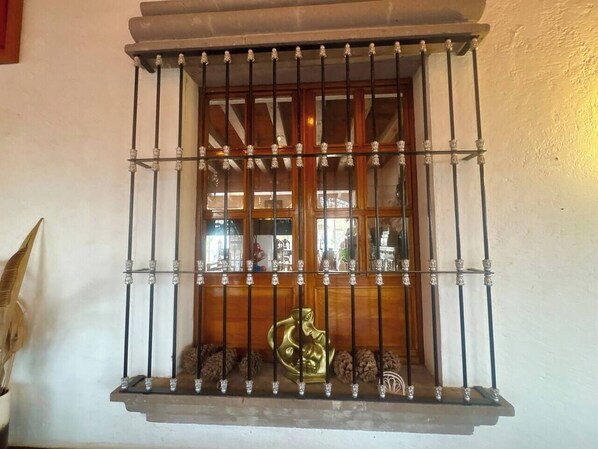 Une fenêtre avec des barreaux en métal et une statue décorative en laiton.