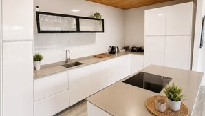 A modern kitchen with white cabinetry, a central island, and a wooden ceiling. - Casa Jimena con Piscina Privada (Torrox)