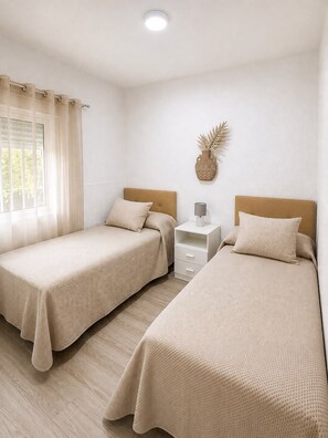 A room with two beds, a nightstand, a lamp, and a decorative wall piece. - Casa Jimena con Piscina Privada (Torrox)