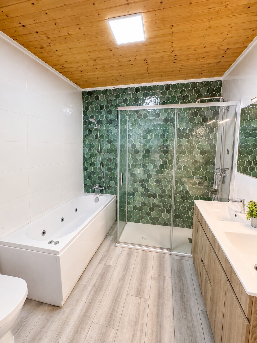 A modern bathroom with a glass-enclosed shower, a freestanding bathtub, and a vanity with a mirror.