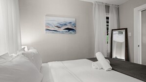 Ein Hotelzimmer mit einem ordentlich bezogenen Bett, einem großen Spiegel und einem Bild an der Wand.