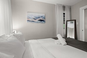 Ein Hotelzimmer mit einem ordentlich bezogenen Bett, einem großen Spiegel und einem Bild an der Wand.