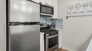 Eine kompakte Küche mit einem Edelstahl-Kühlschrank, einer Mikrowelle, einem Gasherd und einem Backofen.
