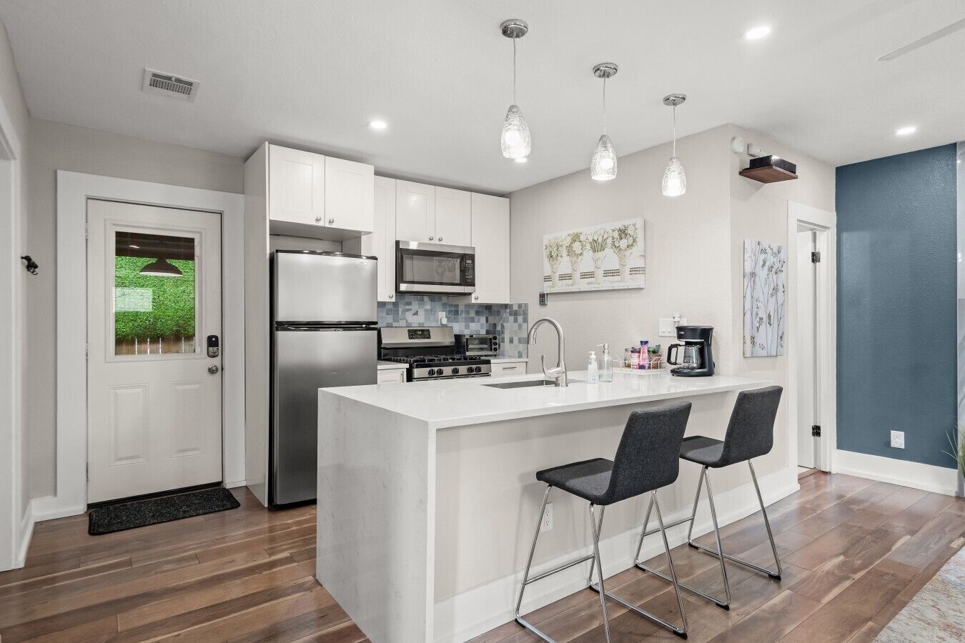 A modern kitchen with a central island, stainless steel appliances, and pendant lighting.