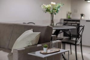 A modern living room with a sofa, a small table with a plant, and a glass on the table.