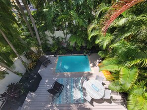 A rooftop pool area with a wooden deck, a pool, and surrounding tropical plants. - Sunset Serenity-Minutes away from the beaches, Old Town and the best of KW! (Key West)