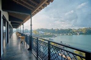 Un balcon avec vue sur une rivière, un pont et une ville lointaine.